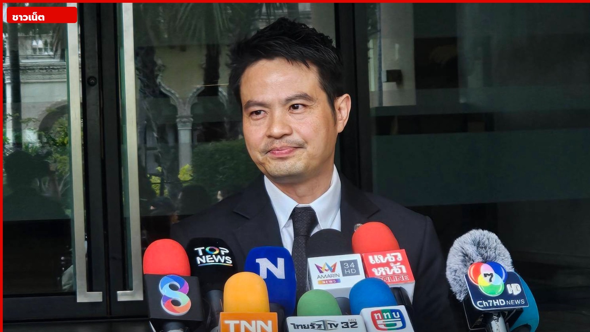 นายภราดรในสูทดำให้สัมภาษณ์สื่อที่ทำเนียบ