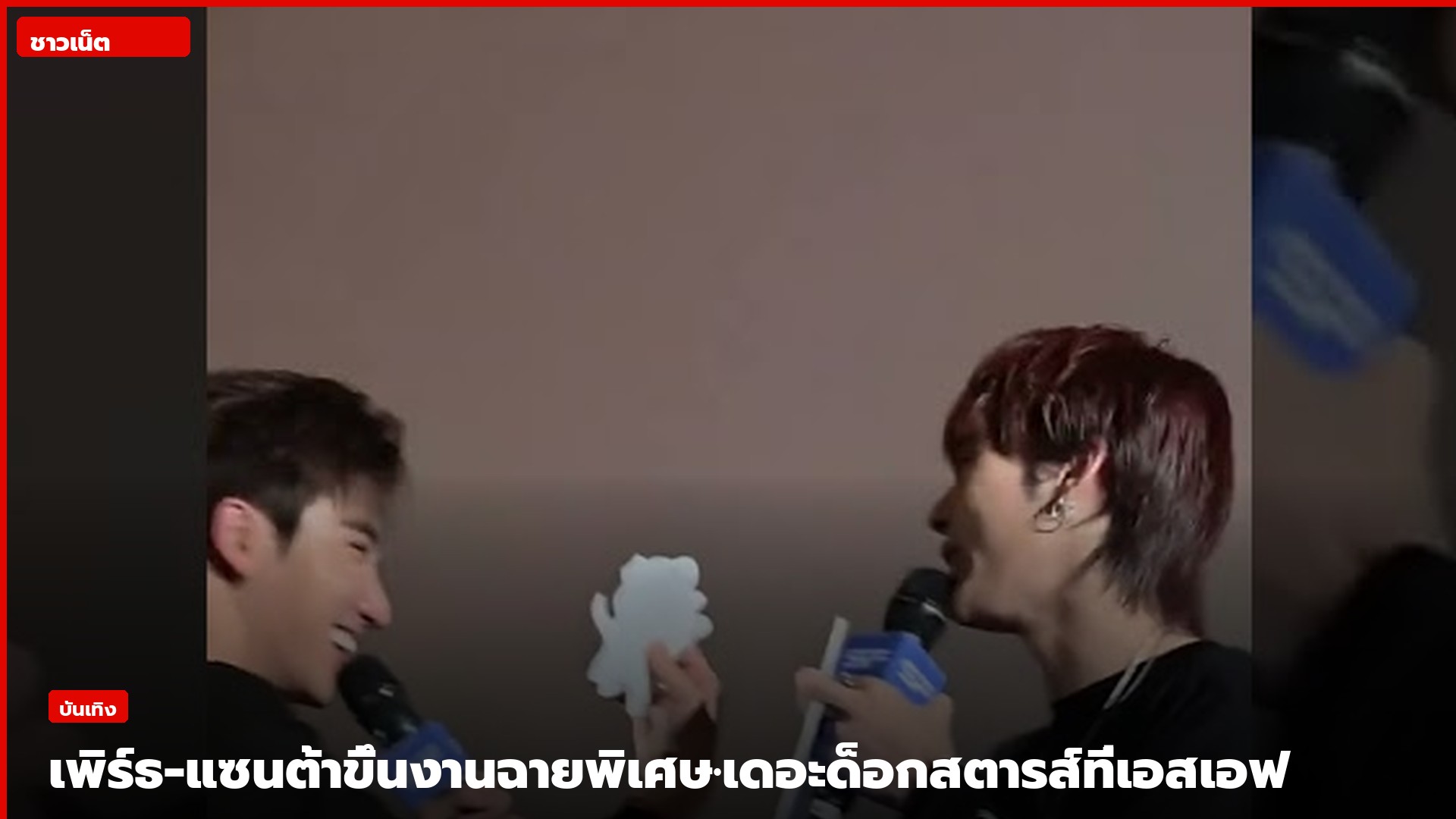 เพิร์ธและแซนต้าถือไมค์ติดโลโก้ SF บนเวทีโรงภาพยนตร์ มีชิ้นตัดกระดาษตัวละคร DOMIIA